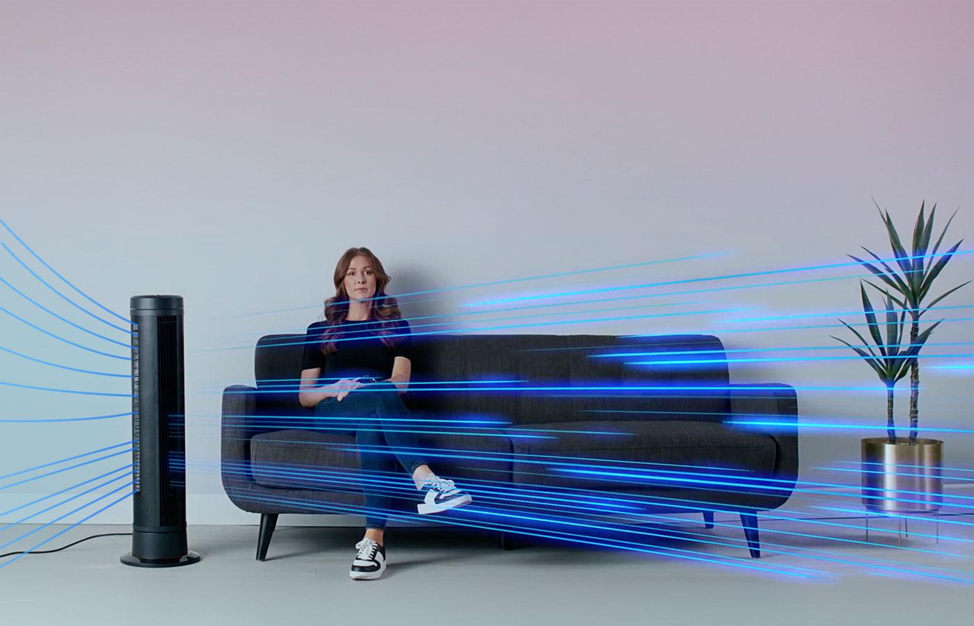 ARA Whole Room Circulation Lifestyle of ARA tower's whole room circulation. A woman sits on her couch as blue streaky lights come out of the ARA tower to the left of her.