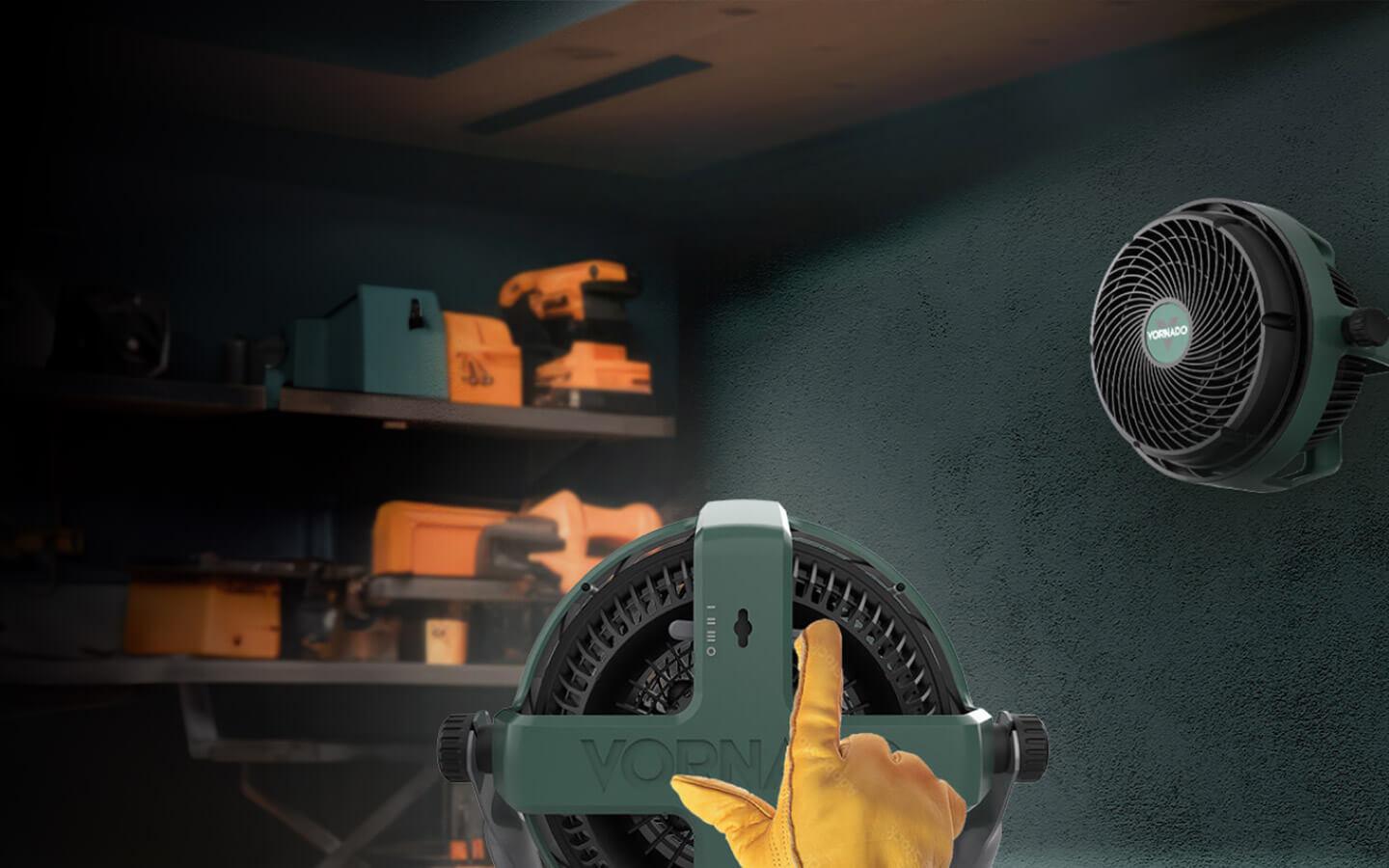 EXO61 HD Hang or Stand An image showing two EXO61 HD fans in a garage. One fan is hanging on the wall. The other fan is centered in the image with a yellow glove adjusting the angle settings.