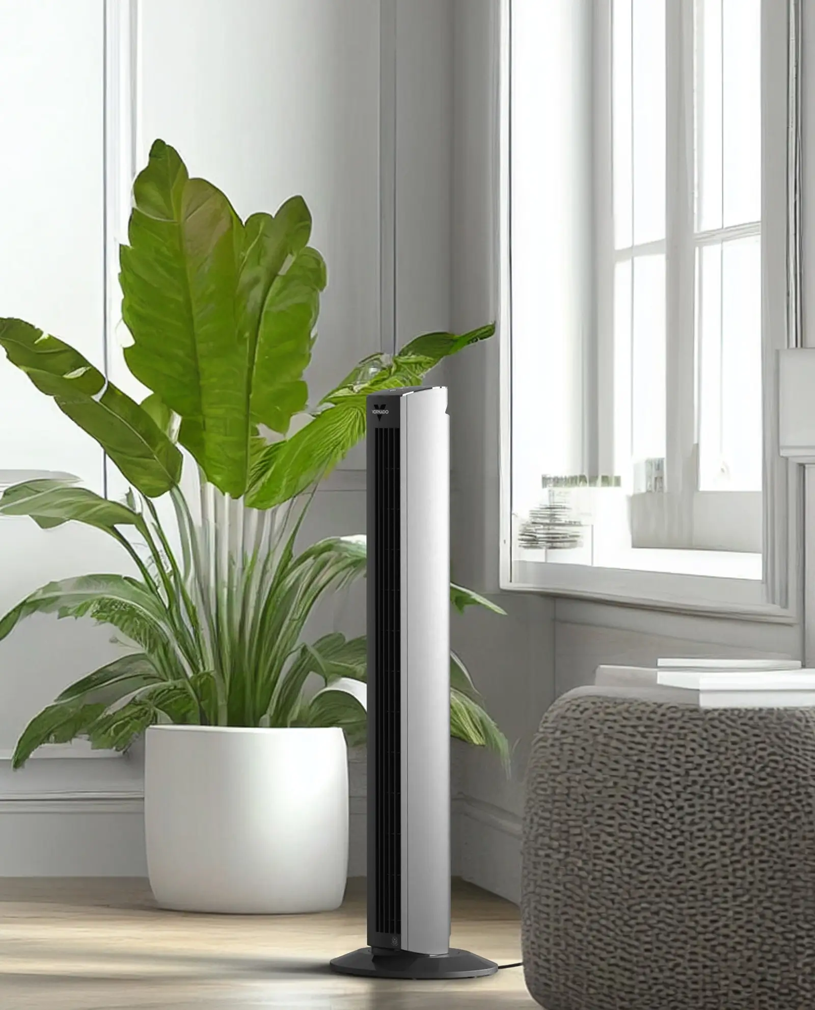 OZI42DC Black Product Lifestyle Lifestyle image of OZI42DC tower fan by a white wall, green plant and a window.